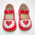 Zapatos rojos de la niña con el corazón grande